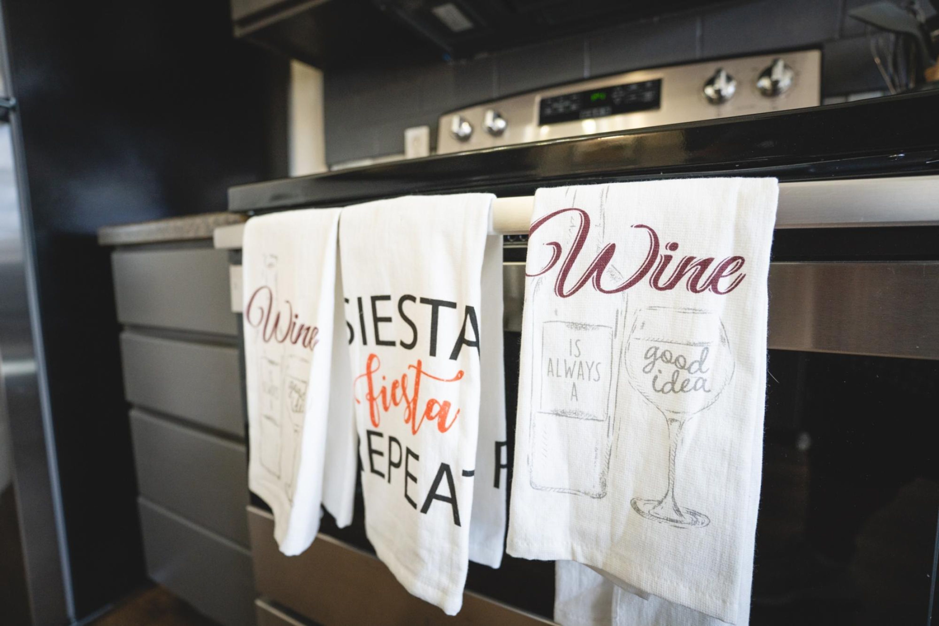 Kitchen towels with text and a wine glass illustration.