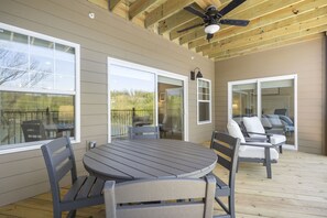 Relax on the deck with a round table and four matching chairs, surrounded by large windows and a ceiling fan.