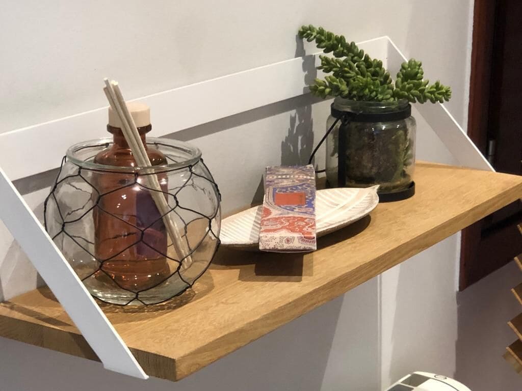 Une étagère en bois avec un bocal en verre, une boîte et une plante en pot.