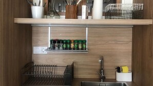 Keittiössä on puiset kaapit, ruostumattomasta teräksestä valmistettu pesuallas ja mausteteline.