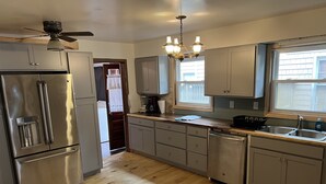 Een moderne keuken met roestvrijstalen apparatuur, houten vloeren en een kroonluchter.
