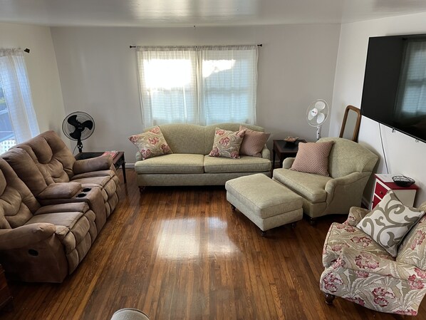 A living room with a brown leather sofa, a beige sectional sofa, and a patterned armchair. - Water Front Oasis 4 Bedroom Home by RedAwning (Norfolk)