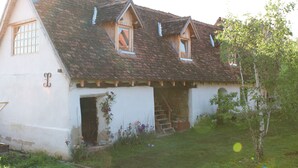 A white building with a sloped roof, a small porch, and a staircase leading to an upper level. - Viscri 9 (Bunesti)
