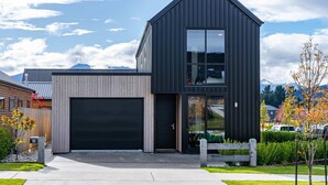 A modern two-story house with a black exterior, a large garage, and a well-maintained front yard. - Amazing Alpine Views in Wanaka (Wānaka)