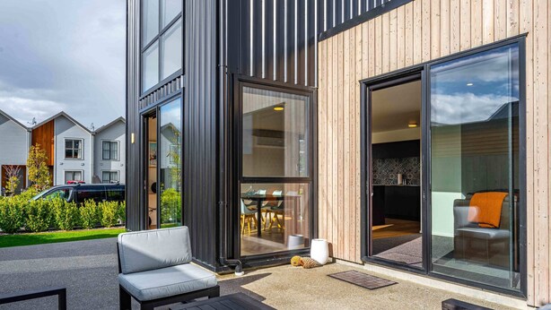 A modern building with large windows, a patio with outdoor seating, and a visible interior space with a dining area. - Amazing Alpine Views in Wanaka (Wānaka)