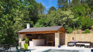 A stone building with a tiled roof, a pool, and a Buddha statue. - Maison Avec Piscine, Dans un Quartier Calme Sans vis à Vis, Près D'une Forêt (Saint-Julien-de-Peyrolas)