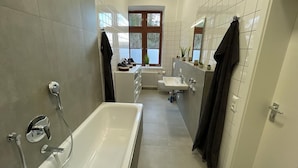 Une salle de bain moderne avec une baignoire, un lavabo et une fenêtre.