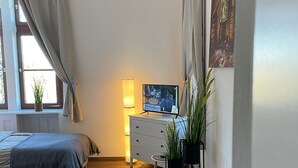 Une chambre avec deux lits, un bureau, une télévision et une fenêtre avec des rideaux.