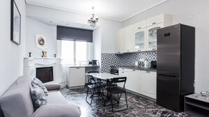 A modern kitchen with white cabinets, a black refrigerator, and a dining area with a marble floor. - Modern apt with Increbilbe Athens Views (Galatsi)