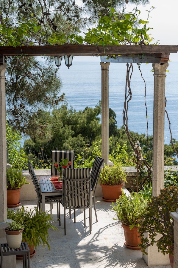 Une terrasse extérieure dotée d’une pergola, de sièges et de plantes en pot.
