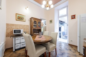Un coin repas comprenant une table ronde, des chaises, un four à micro-ondes, un meuble et un réfrigérateur.