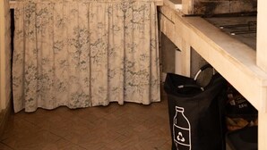 Een keuken met een stenen muur, een koffieapparaat en een prullenbak.