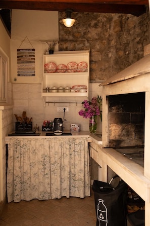 A kitchen with a stone wall, a coffee machine, and a trash bin. - DUBrovnik Seaview Apartment 10 min walk to the Old Town (Dubrovnik)