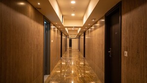 A long, well-lit hallway with wooden walls and a shiny marble floor, leading to a dark door at the end. - Hotel Silver Clé Hitech City (Hyderabad)