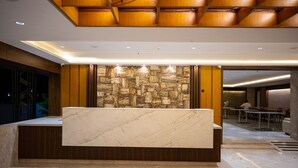 A modern reception area with a marble counter, wooden paneling, and a stone wall. - Hotel Silver Clé Hitech City (Hyderabad)
