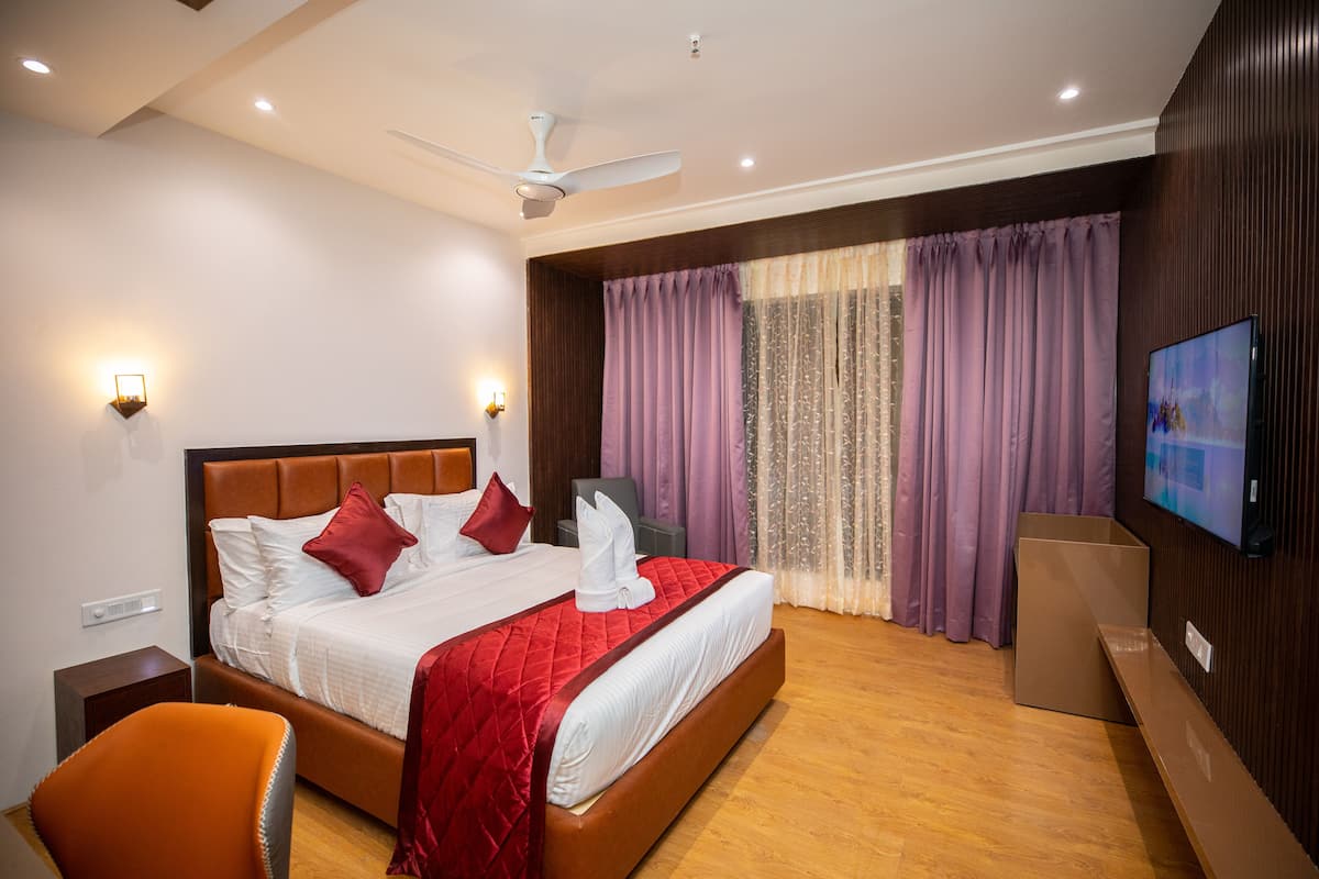 Une chambre d’hôtel avec un grand lit, un ventilateur de plafond, une télévision et un plancher en bois.