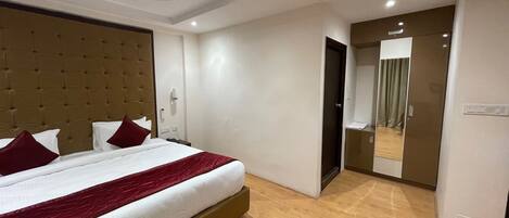 A modern hotel room with a large bed, a ceiling fan, and a mirror on the wall.