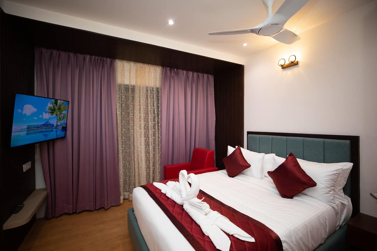 Une chambre d’hôtel dotée d’un grand lit, d’un téléviseur à écran plat, d’un ventilateur de plafond et d’un luminaire fixé au mur.