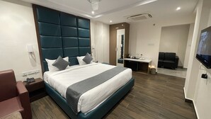 A modern hotel room with a large bed, a desk, a TV, and a seating area. - Hotel Silver Clé Hitech City (Hyderabad)