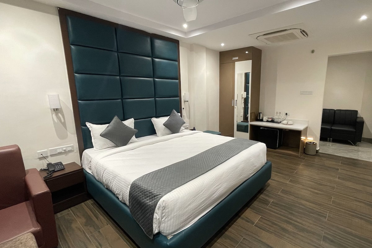 Une chambre d’hôtel moderne équipée d’un grand lit, d’un bureau, d’une télévision et d’un coin salon.