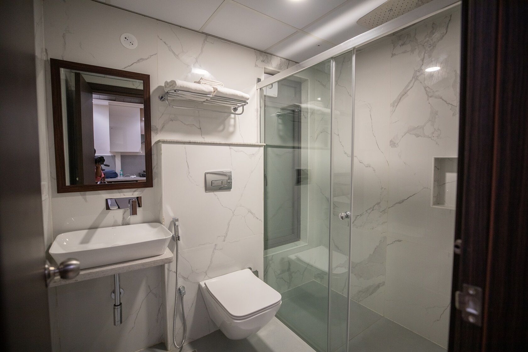 A modern bathroom with a glass-enclosed shower, a white sink, and a mirror above the sink.