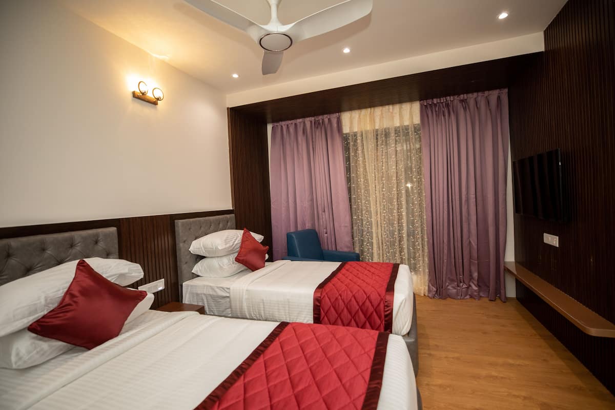 Une chambre d’hôtel avec deux lits, un ventilateur de plafond, une télévision et une fenêtre avec des rideaux.