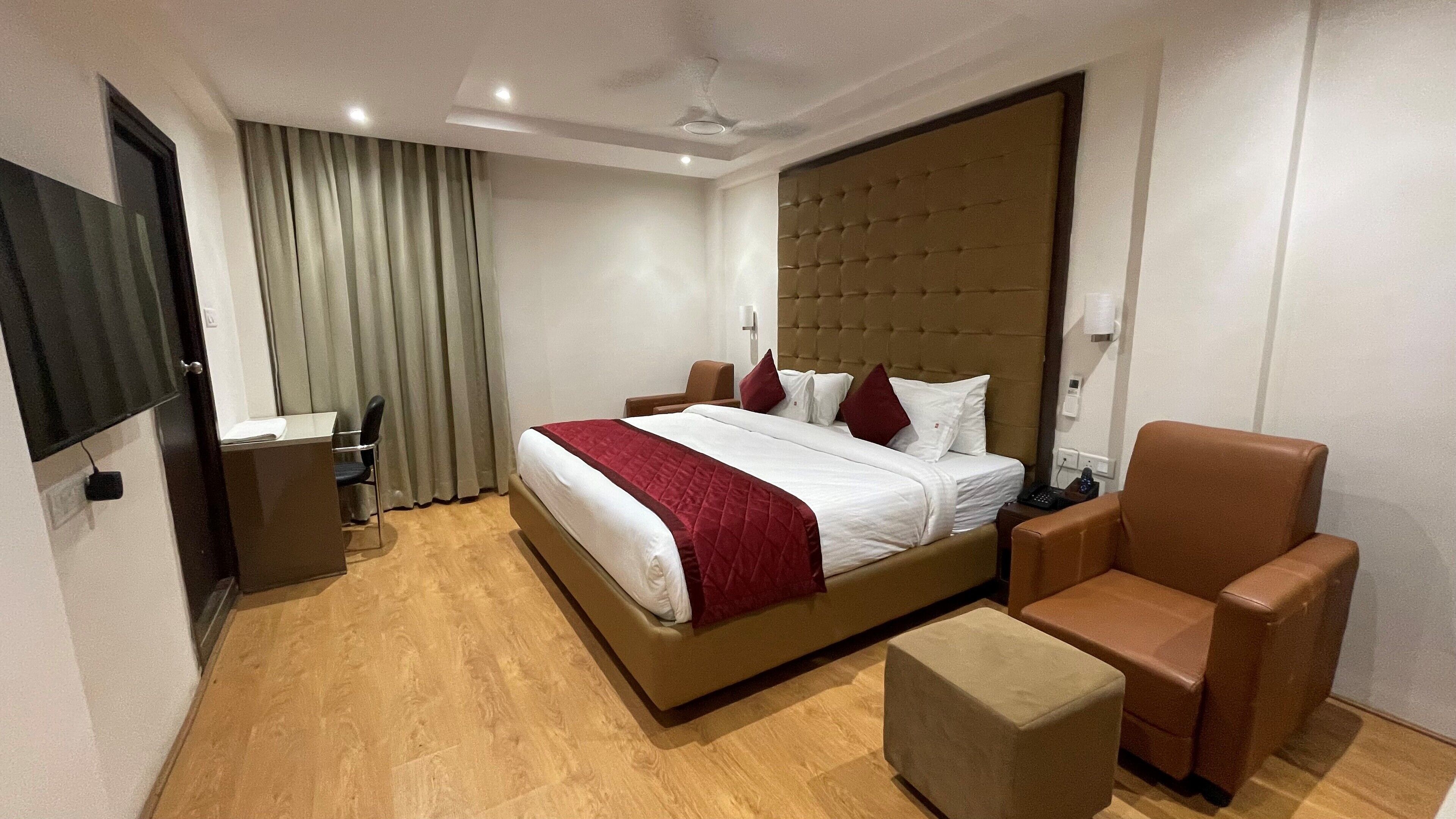 Una habitación de hotel con una cama grande, un escritorio, una silla y un televisor.