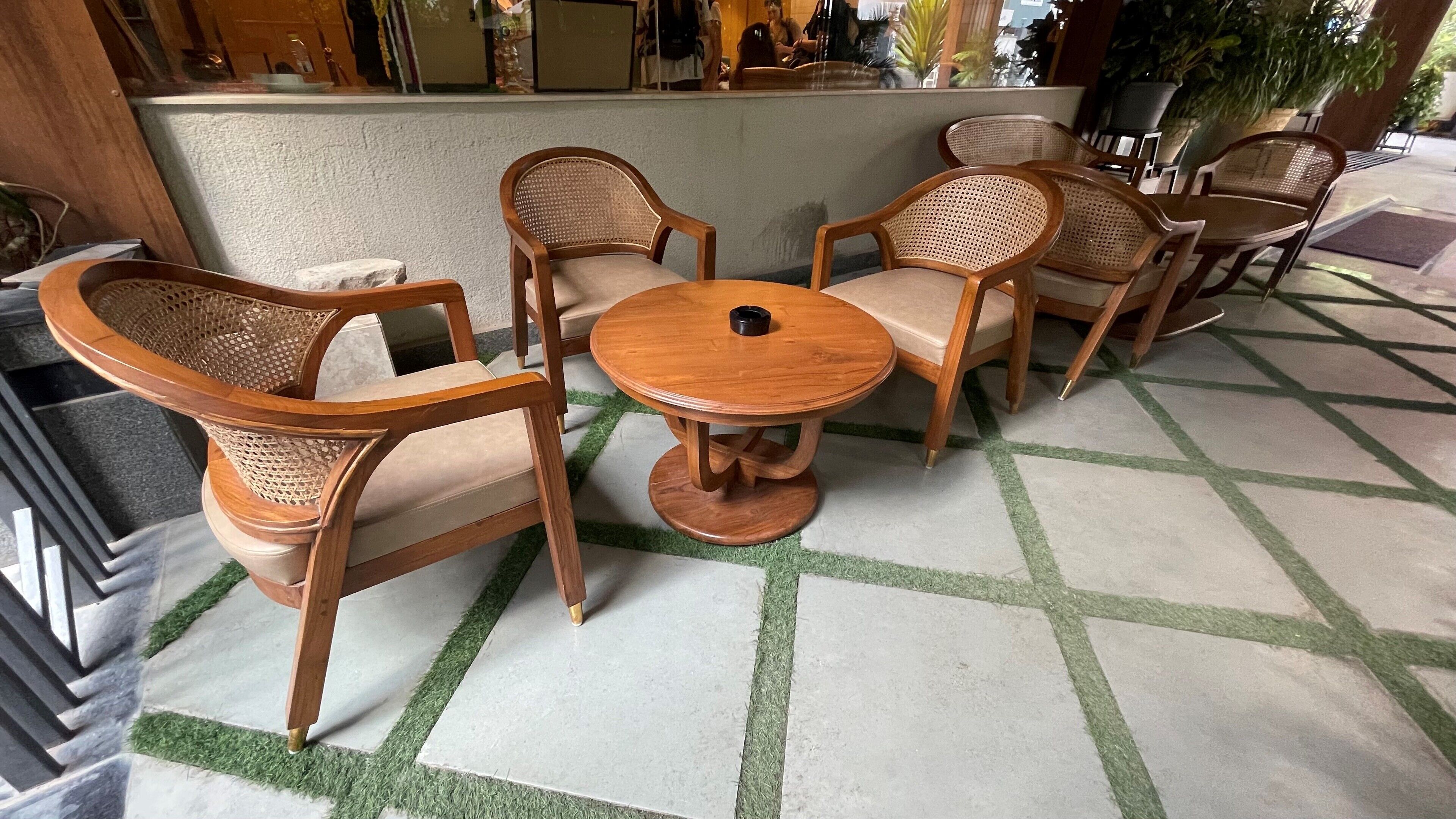 A seating area with wicker chairs and a round table, set on a patterned floor.