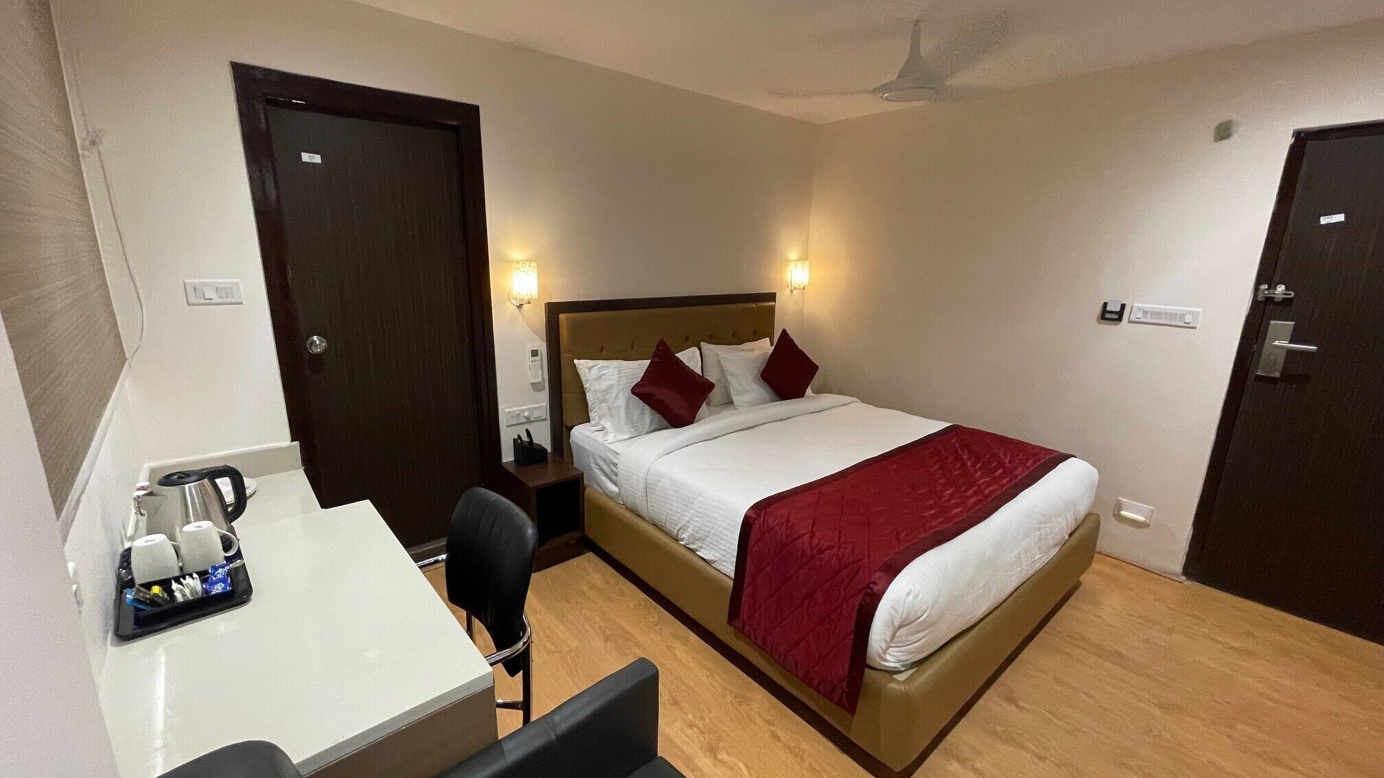 A hotel room with a bed, bedside table, chair, desk, and a ceiling fan.