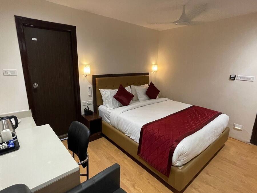 A hotel room with a bed, bedside table, chair, desk, and a ceiling fan.