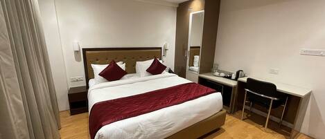 A hotel room with a bed, bedside table, desk, chair, and a mirror.