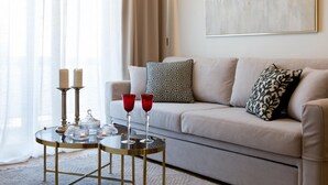 Un salon avec un canapé, une table basse en verre, deux bougies et un tableau accroché au mur.