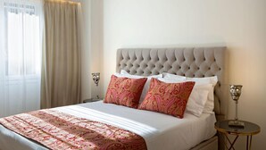Una cama bien tendida con una colcha estampada, un cabecero capitonado y dos mesitas de noche con lámparas.