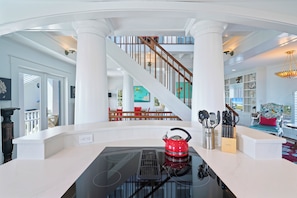 A modern kitchen with a black induction cooktop, a red kettle, and a knife block.