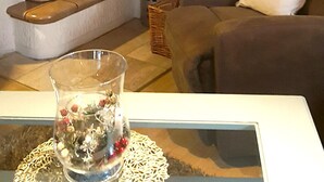A living room with a fireplace, a sofa, a glass vase with flowers, and a basket. - Bungalow directly at the lake, with own boat (Neubäu / Roding)