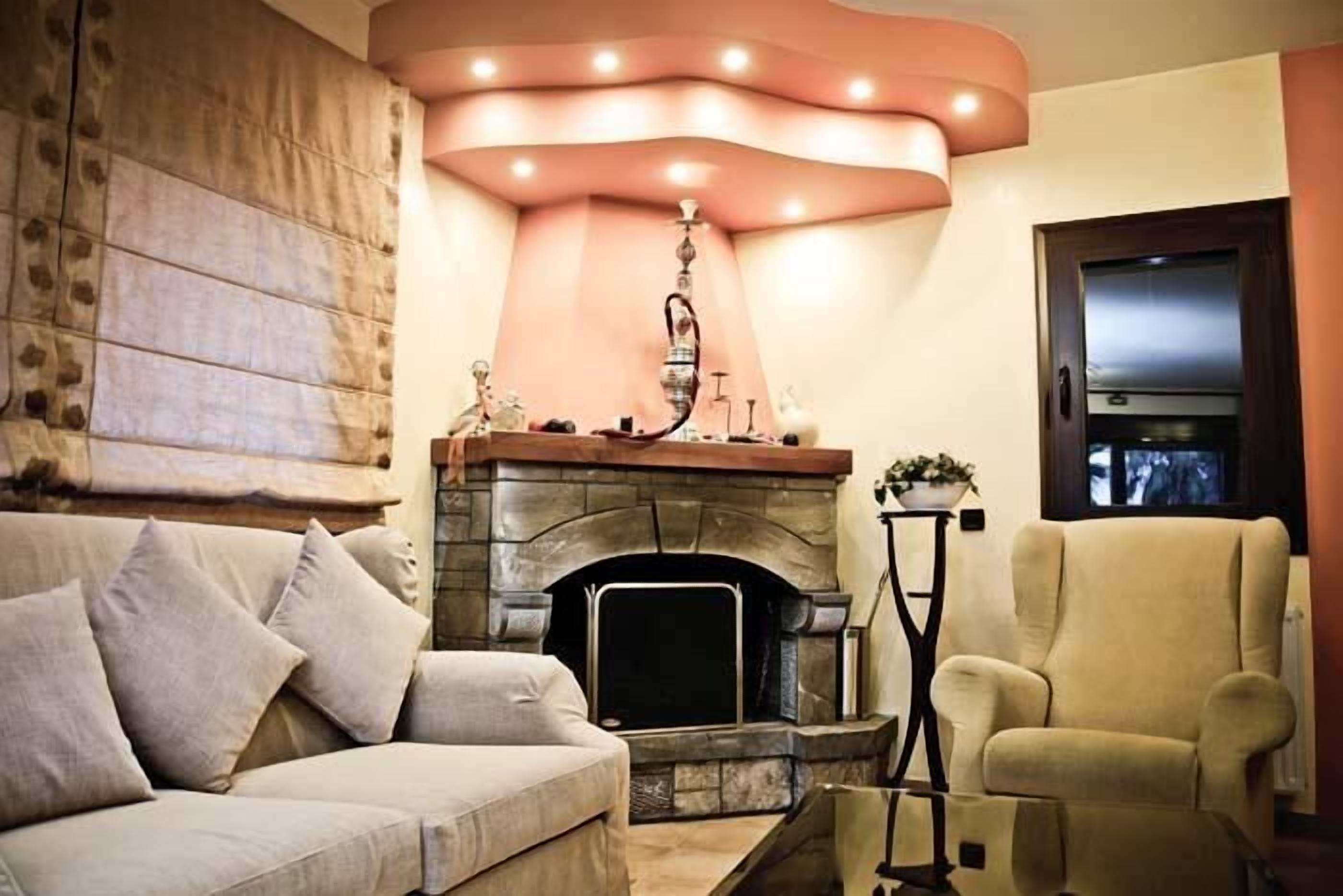 A cozy living room with a stone fireplace, a sofa, and a chair.