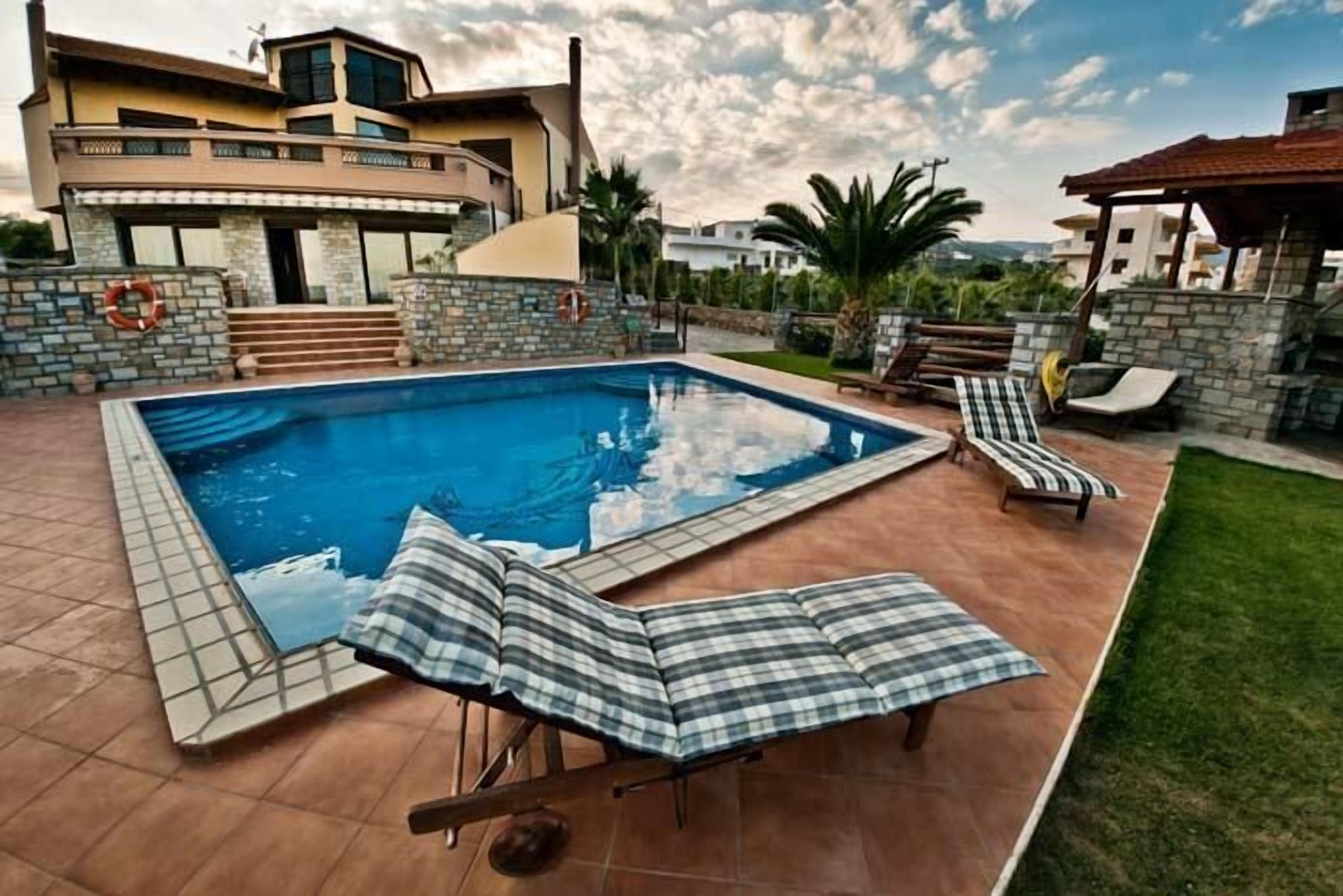 A swimming pool with lounge chairs and a stone wall.