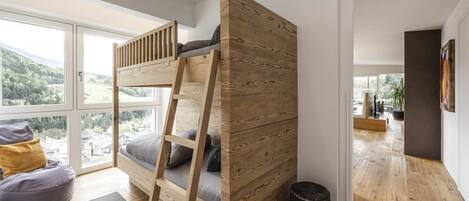 Une chambre moderne avec un lit superposé, de grandes fenêtres et une vue sur un paysage montagneux.