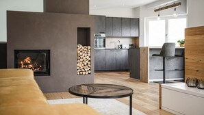 A modern living room with a fireplace, a kitchen in the background, and a dining area with a wooden table and chairs. - Dolomites Alpin Penthouse 90 qm with privat sauna and privat whirlpool, WLAN (Rio di Pusteria)
