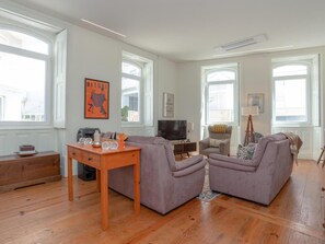 A spacious living room with a wooden coffee table, two sofas, a television, and a painting on the wall. - Casa do Poeta (Figueira da Foz)