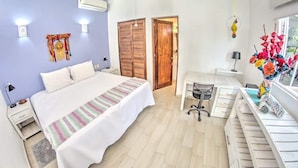Une chambre à coucher comprenant un lit, des tables de chevet, un bureau, une chaise, une armoire et un appareil de climatisation.
