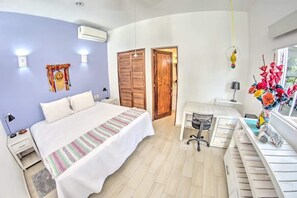 Une chambre à coucher comprenant un lit, des tables de chevet, un bureau, une chaise, une armoire et un appareil de climatisation.