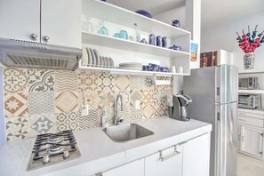 Une cuisine moderne avec des armoires blanches, un évier en acier inoxydable et un pare-feu décoratif.
