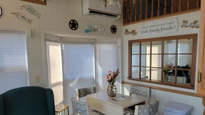 A dining area with a table and chairs, a vase with flowers, and a window with a view.