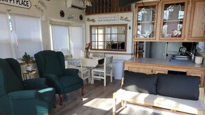 A cozy living room with a dining area, wooden cabinets, and a kitchen area.