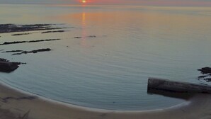 A beach scene with a sunset over calm waters, a sandy shore, and a concrete structure. - Cosy Seaside Home with Free Parking - Pass the Keys (North Shields)