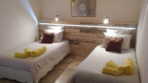Two single beds with white linens and brown pillows, a wooden headboard, and a wall-mounted mirror. - The southern sun - 4 people (ST JEAN DE VALERISCLE)