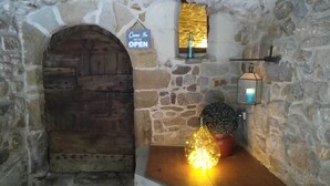 A stone-walled room with a wooden door, a 'Come In We're Open' sign, a lantern, and a potted plant. - The southern sun - 4 people (ST JEAN DE VALERISCLE)
