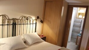 A hotel room with a bed, a wooden door, and a view of a laundry area.