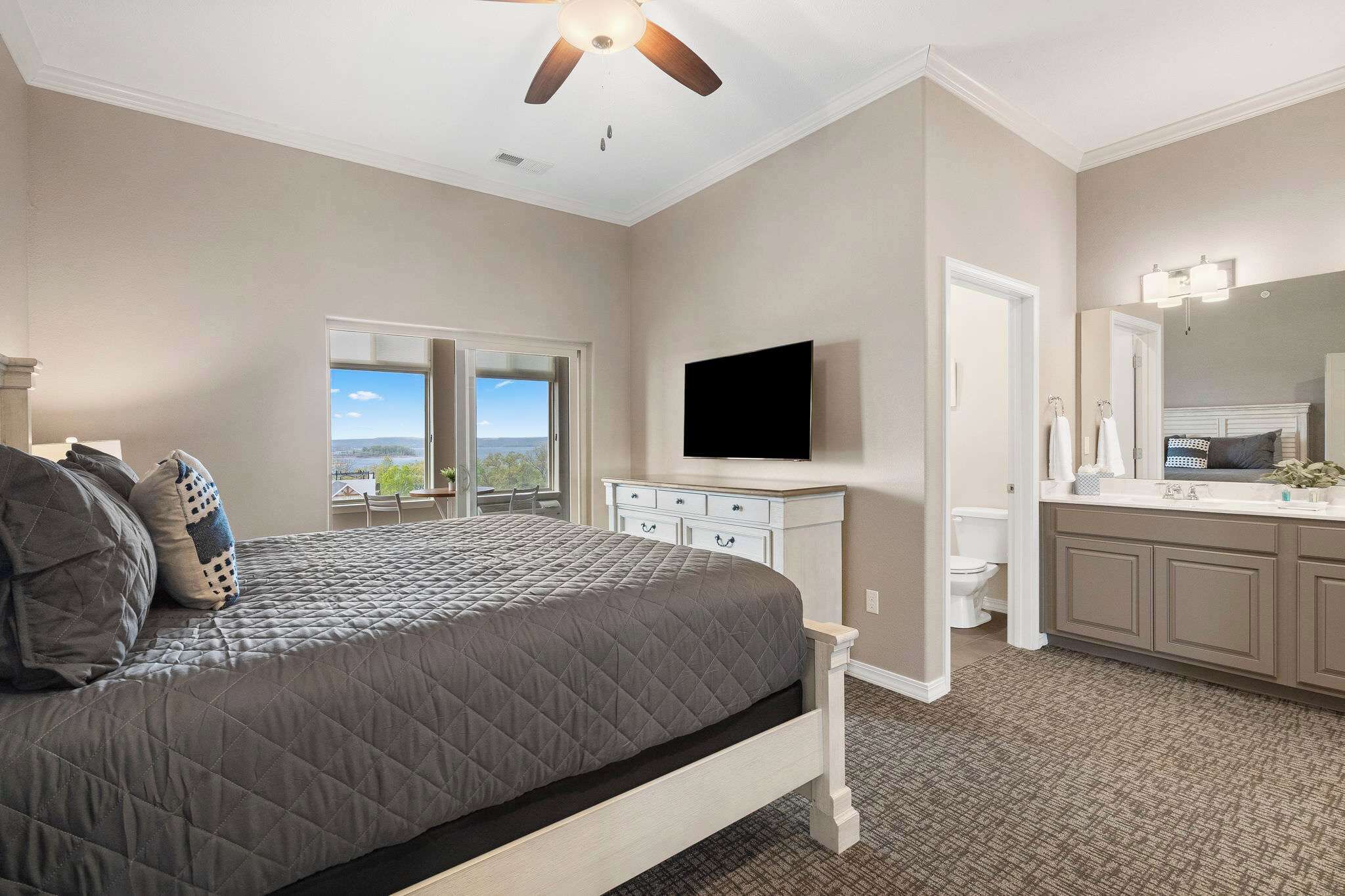 Une chambre à coucher comprenant un lit, une télévision, une commode et une salle de bain avec des toilettes et un lavabo.